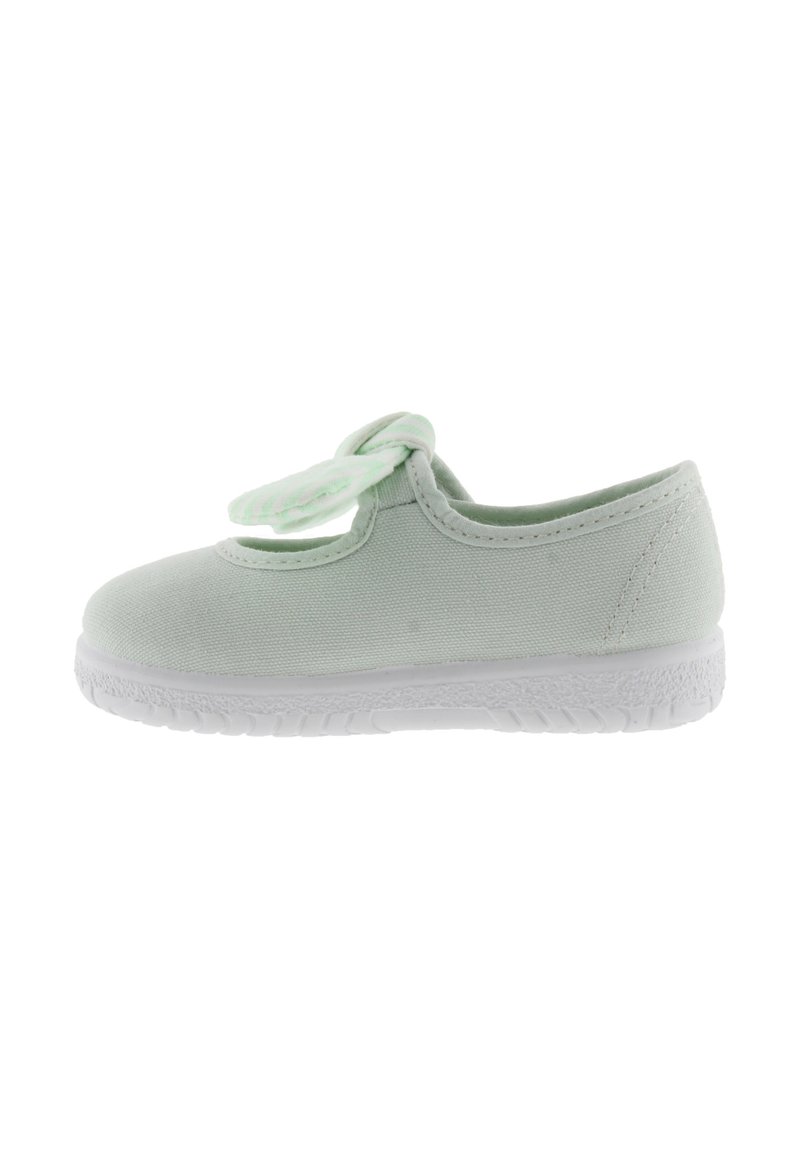 Zapatilla de lona verde claro con punta redonda, suela de goma blanca y detalle de lazo decorativo en el borde superior. Textura suave, diseño sencillo.