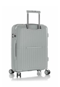 Maleta de mano rígida en gris claro, con surcos verticales, dos ruedas suaves y un mango metálico extensible.