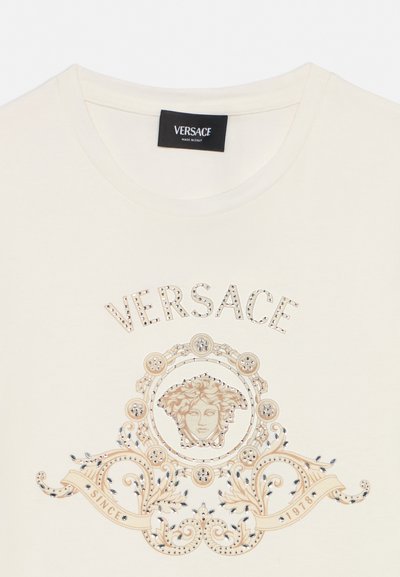 Cream Versace T-shirt with studded logo, Medusa head emblem, ornate scrollwork, and "Since 1978" banner on front.