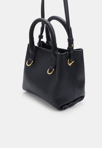 Borsa in pelle nera con texture, due manici arrotondati, tracolla regolabile e anelli in metallo dorato su uno sfondo bianco.