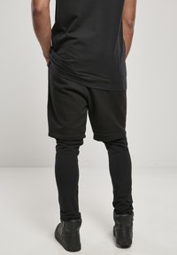 Sorte athletic shorts lagd over sorte leggings, med en avslappet passform. Sorte høyhælte sneakers fullfører antrekket.