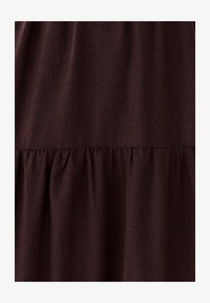 Bruine stof met een gestructureerd oppervlak. Heeft een gerimpelde naad aan de onderkant, wat wijst op een gelaagd ontwerp. Soepel, lichtgewicht materiaal.