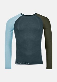 Long-sleeve shirt in dark blue, light blue, and olive green. Features a fitted design, contrasting sleeves, and a white logo at the hem.
