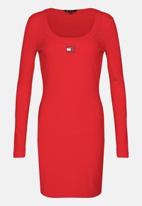 Robe rouge à manches longues en maille côtelée avec décolleté rond et petite étiquette du logo Tommy Jeans centrée sur la poitrine.