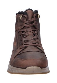 Bruine leren veterschoen met zwarte fleece voering en beige rubberen zool, weergegeven van de voorkant op een witte achtergrond.
