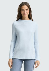 Helles blaues, geripptes Langarmoberteil mit einem Bootsausschnitt. Weicher Stoff, figurbetonter Schnitt und gerader Saum. Kombiniert mit hellblauen Jeans.