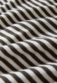 Raidallinen kangas ruskean ja kerman sävyissä, jossa on nauhamainen rakenne ja tasaisin välein vaakasuorat raidat. Pehmeä ja taiteltu.