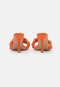 Sandales à talons hauts orange avec design de brides tressées, bout pointu et talon stiletto fin. Finition en cuir lisse et semelle intérieure rembourrée.