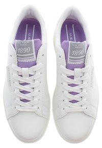 Sneaker bianche con texture liscia, dotate di una soletta viola e branding sulla linguetta. I lacci sono bianchi e la suola è piatta e minimalista.