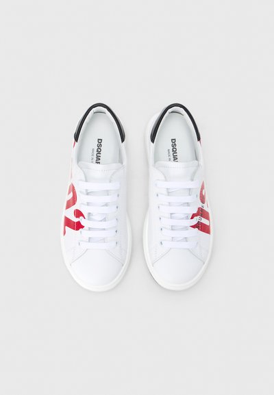 Baskets blanches avec un logo rouge imprimé sur le côté, des accents noirs au talon et des lacets plats. Texture lisse et design discret.