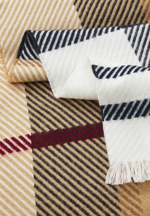 Wool scarf featuring diagonal stripes in beige, navy, and white with a fringed edge. The pattern includes a bold red line across.