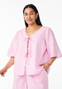 Pink and white striped short-sleeved blouse with a V-neck and tie closure. Fabric appears lightweight with a relaxed fit and soft texture.