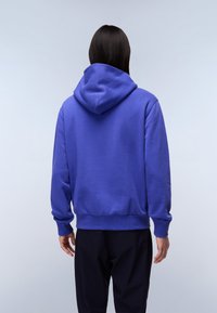 Felpa viola con cappuccio regolabile, polsini e orlo a costine. Il tessuto sembra morbido e spesso, con una superficie liscia.