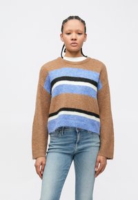 Pulover maro tricotat cu dungi albastre, negre și albe. Design scurt, croială lejeră și guler răsucit. Asortat cu blugi deschiși la culoare.