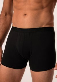 Boxer-briefs en coton noir avec une taille élastique douce arborant un logo en relief. Le design comprend une coupe ajustée avec des coutures lisses.