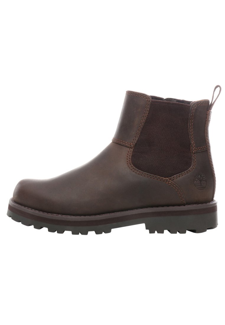Bota de tobillo de piel marrón con paneles laterales elásticos, puntera redondeada y suela de goma texturizada con un logo en el lado exterior.