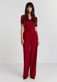 Top corto a maniche corte a righe rosse abbinato a pantaloni a gamba larga in vita alta dello stesso colore. Texture liscia e design su misura con passanti per cintura.