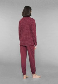 Set di pigiama bordeaux con una maglia a maniche lunghe a fantasia e pantaloni abbinati. Tessuto morbido con polsini elastici alle caviglie.