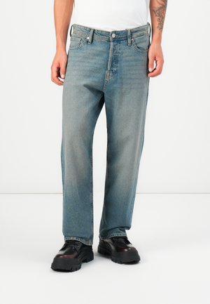 Light blue denim jeans with a loose fit, five-pocket design, and a button closure. Worn with black chunky-soled shoes and a white t-shirt.
