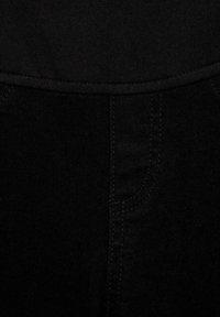 Černá denimová látka s hladkou texturou, s pasem a viditelnými švy. Detailní záběr zdůrazňuje jednoduchost a uniformitu barev.