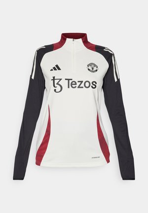 Jersey blanco de manga larga con cuello alto, acentos en negro y rojo, que presenta el logo del Manchester United y la marca Tezos. Material Aeroready.