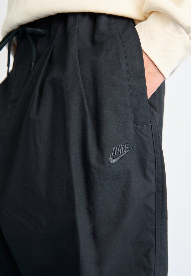 Pantaloni neri Nike con vita elasticizzata e cordoncino, caratterizzati da un discreto logo ricamato sul fronte. Tessuto morbido e leggero.