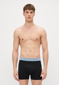 Schwarze Baumwoll-Boxershorts mit einem hellblauen Calvin Klein Logo-Bund, enganliegendem Design und mittelhohem Schnitt. Glatte Textur, keine Muster.
