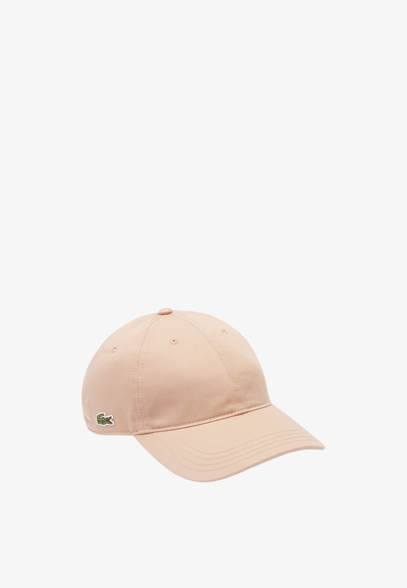Casquette de baseball en coton beige avec une visière incurvée, six panneaux et un logo crocodile brodé vert sur le côté. Texture lisse.