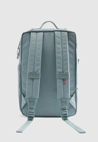 Φωτεινό γαλάζιο σακίδιο με επενδεδυμένους ιμάντες ώμου, υφασμάτινη υφή, διπλό φερμουάρ και θηλιά χειρολαβής στην κορυφή για εύκολη μεταφορά.