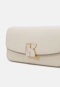 Light beige leather clutch bag with a structured shape, gold hardware clasp featuring a geometric logo, and contrasting dark stitching detail.