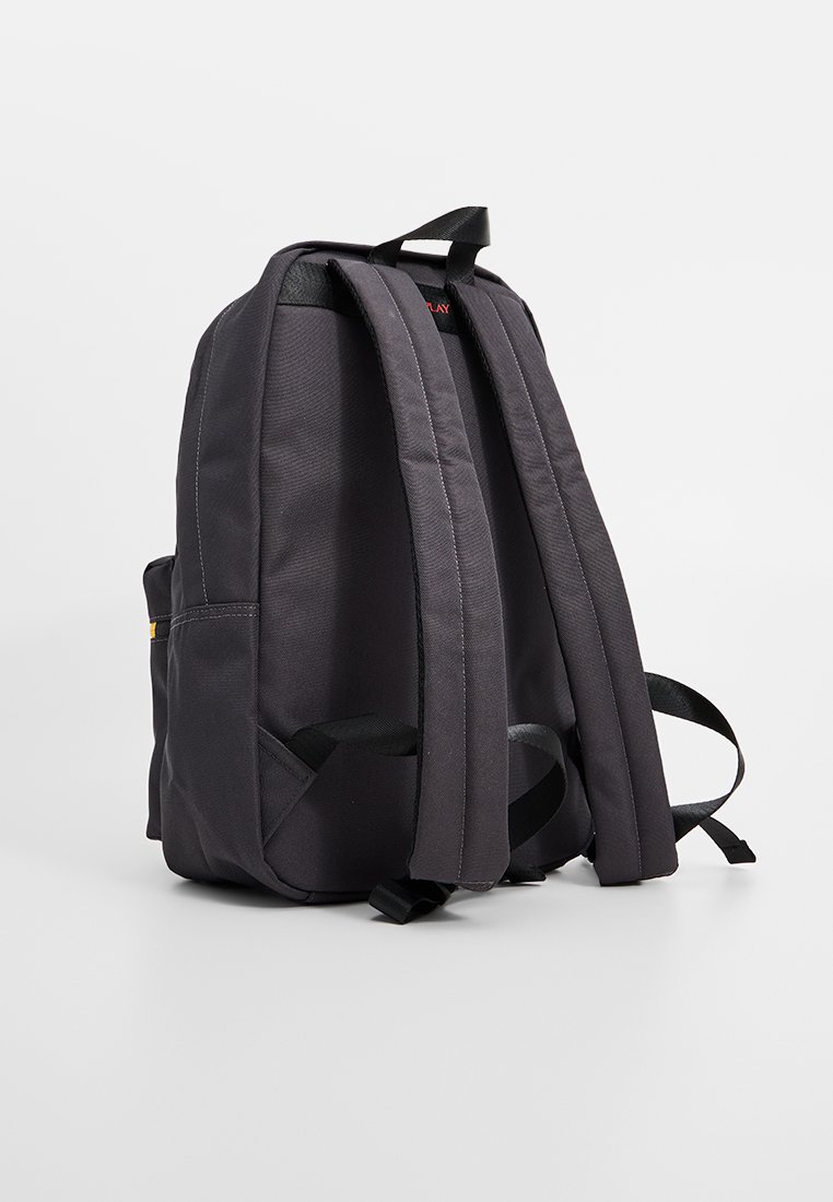 Zaino in tessuto nero con spallacci imbottiti e maniglia, mostrato da dietro su uno sfondo bianco semplice.