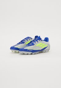 Kék és neon sárga futballcipők, szintetikus felsőrésszel, fűzős kialakítással és formázott tüskékkel a tapadásért. Különleges "F50" logóval.