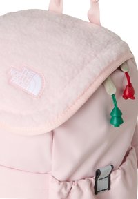 Pink backpack with a soft, textured fleece flap, featuring a white logo, contrasting colored zipper pulls, and a side cinch pocket.