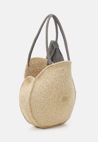 Borsa a rete di paglia intrecciata di colore naturale, con due manici a strisce e un accento annodato, dal design arrotondato e asimmetrico.