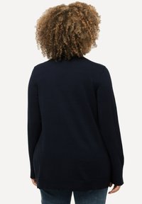 Mörk marinblå långärmad cardigan i ett strukturerat stickat material, med rak passform och ribbad nederdel. Bakifrån visar den en avslappnad passform och mjukt material.