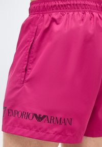 Φωτεινά ροζ σορτς με ελαστική μέση και πλαϊνή τσέπη, με μαύρο λογότυπο Emporio Armani κοντά στο τελείωμα.