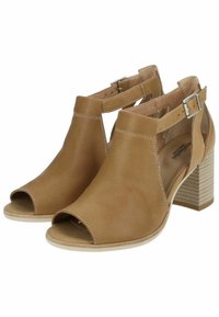 Open-toe heeled sandals made of tan perforated leather, featuring straps with silver-tone buckles and stacked block heels.
