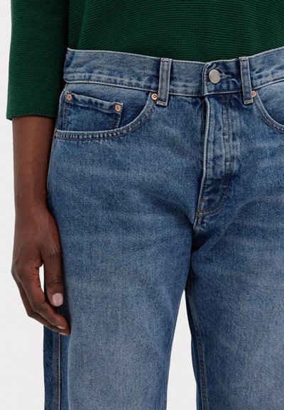 Blue denim jeans with a straight cut, five pockets, and copper rivets. The fabric shows a light wash and subtle fading details.