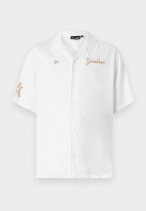 White short-sleeve button-up shirt, featuring "Yankees" in gold embroidery and a logo patch on the left chest and right sleeve.