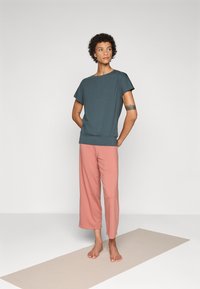 Gray short-sleeve top with a rounded neckline paired with loose, pink cropped pants. Soft fabric with minimal seams, suitable for casual wear.