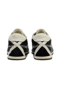 Zapatos de ante y cuero negros con un diseño de tira cruzada blanca, acentos texturizados y detalle de costura en la parte trasera. Suela de goma.