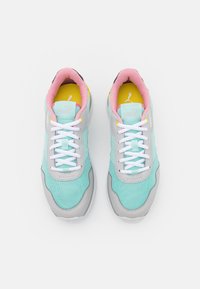 Pair of turquoise and gray Puma sneakers with white laces, pink inner lining, and yellow insoles viewed from above on a white background.