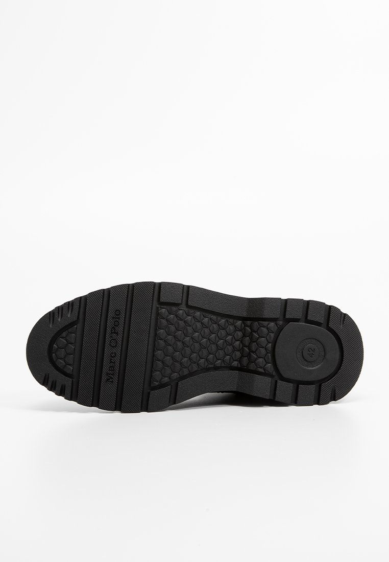 Schwarze Gummisohle mit strukturiertem Griff, sechseckigen Mustern und erhabenen Abschnitten. Beinhaltet einen kreisförmigen Bereich mit der Aufschrift "42."