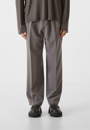 Light gray, wide-leg trousers made of smooth fabric, featuring a simple design with front pleats. Paired with black, textured shoes.