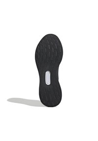 Semelle de chaussure noire avec motif de bande de roulement texturé et élément rectangulaire de coussin blanc au centre, projetant une ombre douce sur fond blanc.