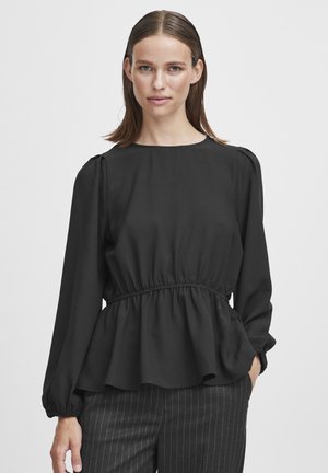 Black long-sleeve blouse with a round neckline, elastic waist, and peplum design. Smooth fabric with slight sheen. Paired with striped trousers.