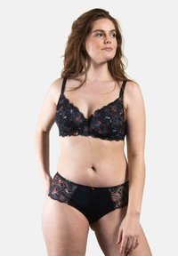 Soutien-gorge en dentelle noire et culotte assortie avec broderie florale, bords festonnés et texture contrastante sur les côtés.