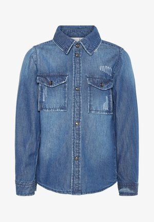 Blå denimskjorte med lange ærmer, knapper foran, to brystlommer med knaplukning og diskrete falmede slidmærker på lommerne og nær kraven.