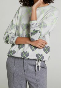 Světlounce šedý svetr se vzory šedých srdcí, zvýrazněný neonově zelenými zkříženými linkami. Manžety zdobí nápis "LOVE". Měkká pletená látka.