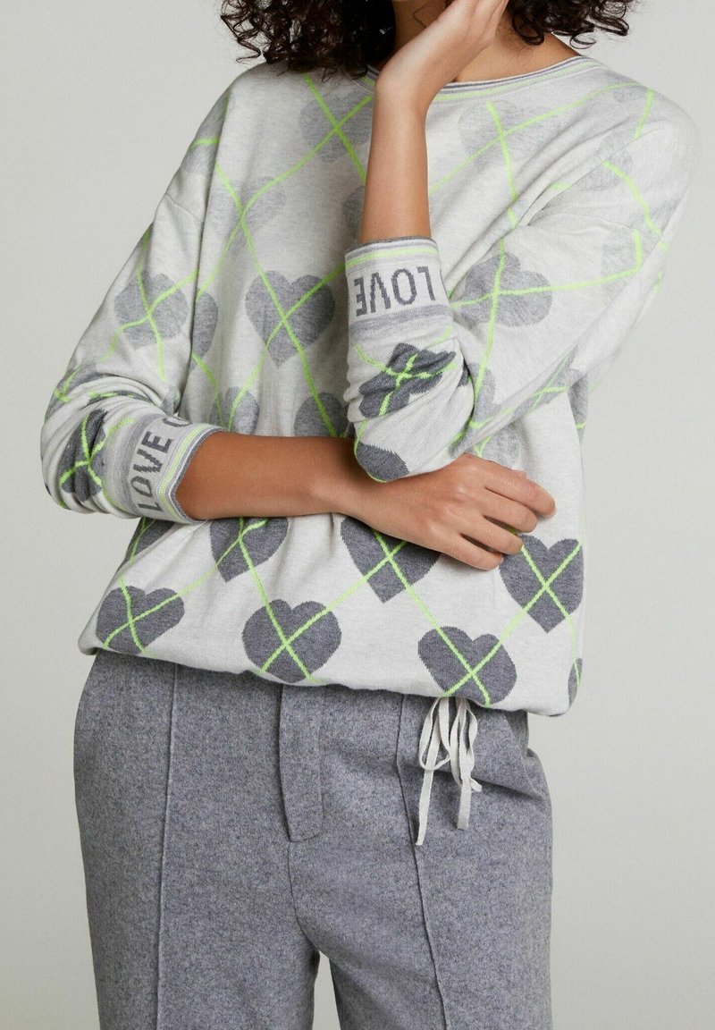 Světlounce šedý svetr se vzory šedých srdcí, zvýrazněný neonově zelenými zkříženými linkami. Manžety zdobí nápis "LOVE". Měkká pletená látka.